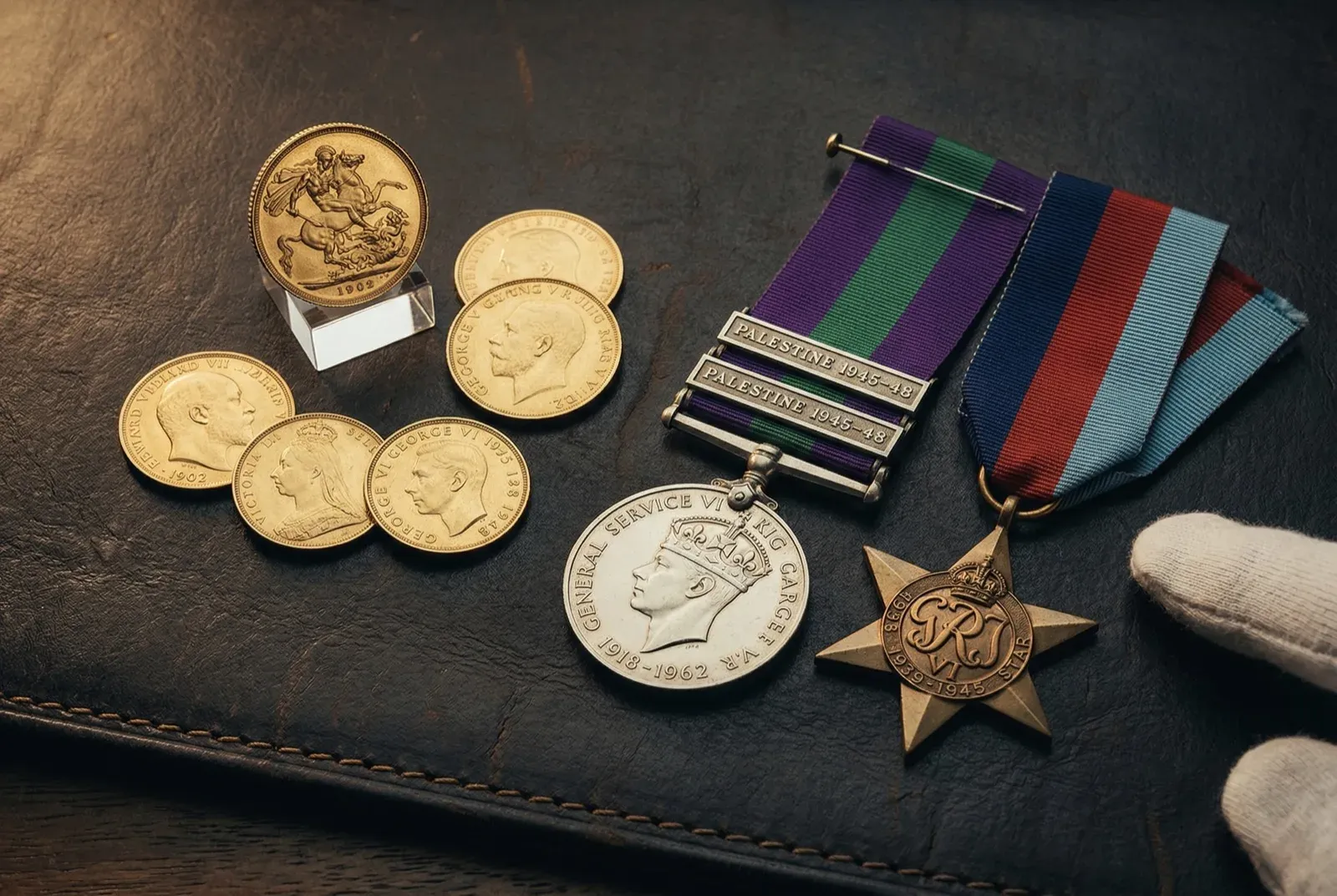 Gold sovereigns and military medals on a leather surface